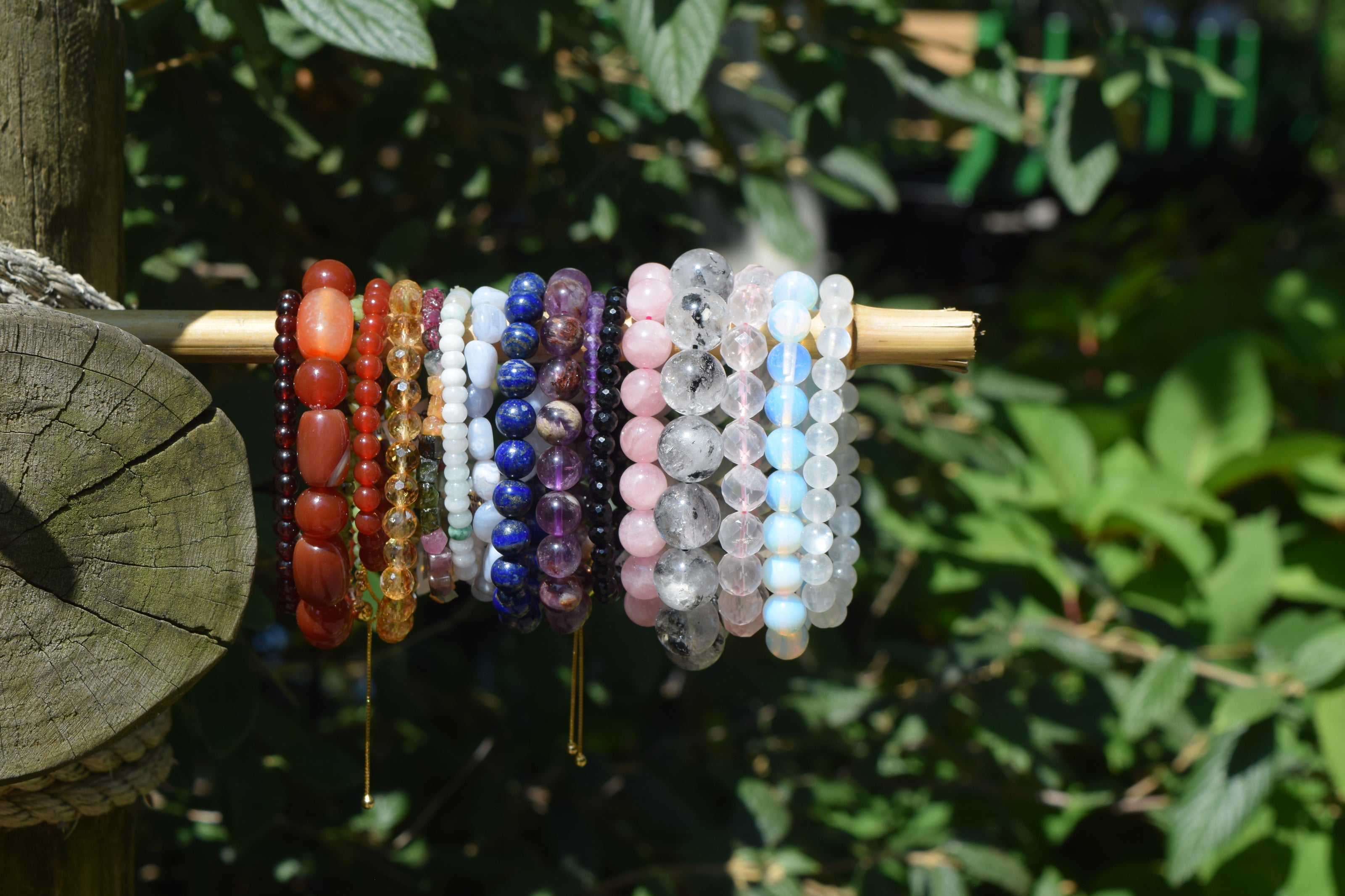 A variety of crystal bracelets displayed on a wooden stick